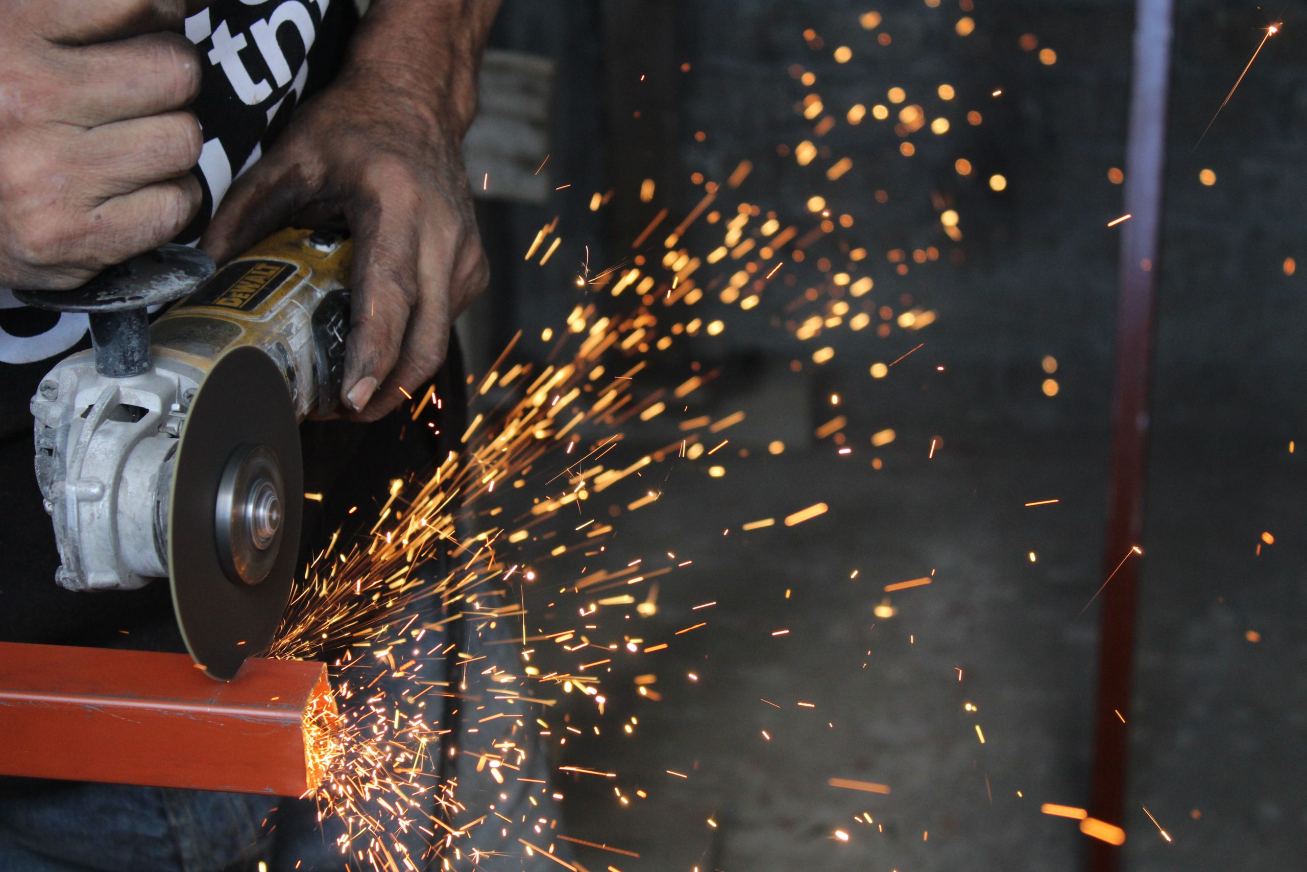 A worker using a power tool creates sparks while cutting metal, showcasing industrial craftsmanship.
